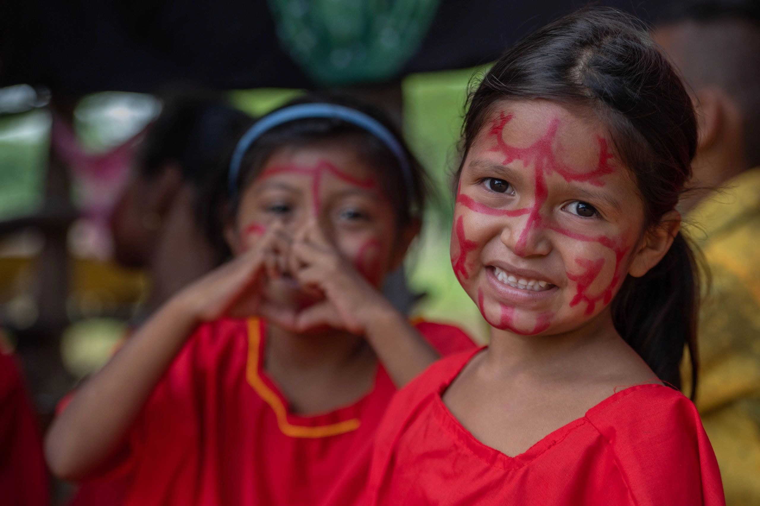 Children with face paint smiling at a cultural event